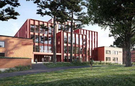 Modern architectural design of the Relex building, featuring a red facade with large glass windows, surrounded by greenery and trees, with people walking along a pathway.