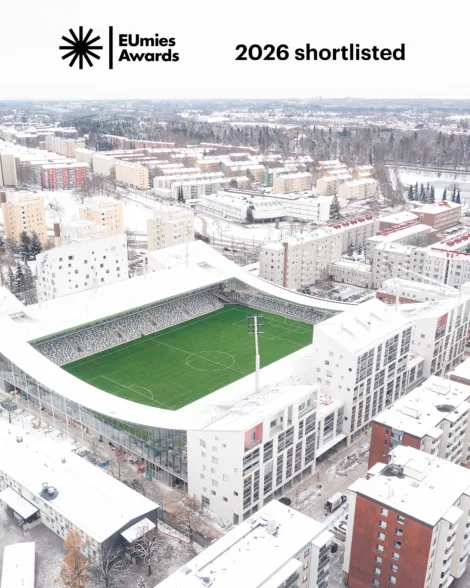 Aerial view of a modern stadium surrounded by residential buildings in a snowy landscape, showcasing the venue shortlisted for the 2026 EUmies Awards.
